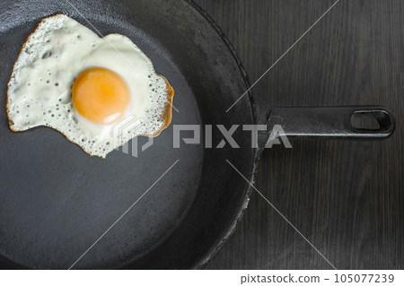 pan with fried eggs on a wooden background 105077239