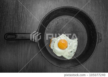 pan with fried eggs on a wooden background 105077240