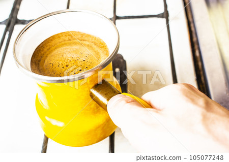 Coffee is brewed in a yellow bale on the stove. 105077248