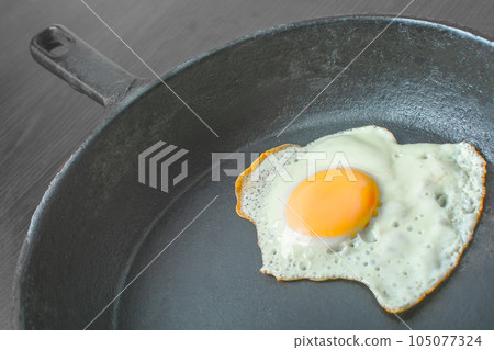 scrambled eggs in a cast iron skillet. Isolated on dark painted wood from above. 105077324