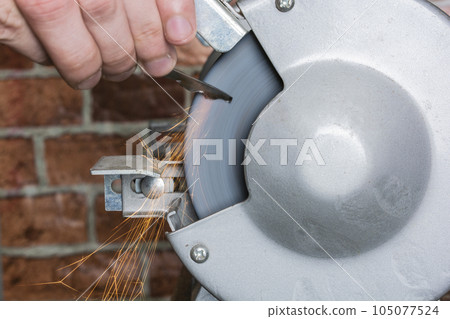 Knife sharpener and hand with blade on wooden table, closeup Knife sharpener and hand with blade on wooden table, closeup 105077524