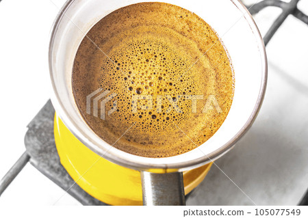 kitchen interior - cooking coffee in a yellow turkey turka on a gas stove 105077549