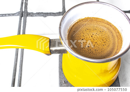 kitchen interior - cooking coffee in a yellow turkey turka on a gas stove 105077550