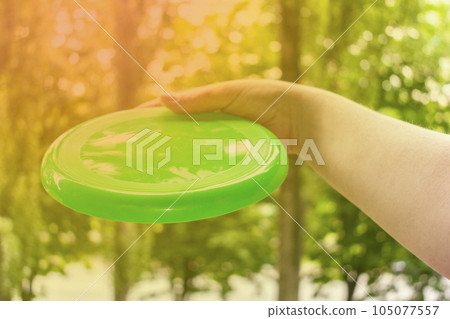 hand throwing a frisbee disc in the park on a summer day hand throwing a frisbee disc in the park on a summer day 105077557