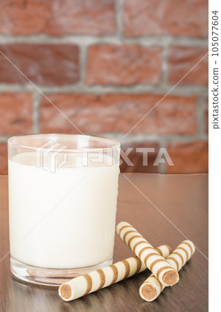 a glass of yogurt with a waffle straw on a black background and a brick wall a glass of yogurt with a waffle straw on a black background and a brick wall 105077604
