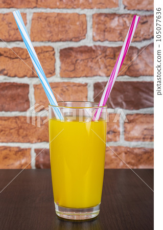 Orange juice Two straws Vitamins Health concept wooden background and brick wall Orange juice Two straws Vitamins Health concept wooden background and brick wall 105077636
