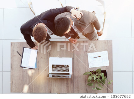 Two successful smiling businessmen are working on a laptop. view from above 105077692