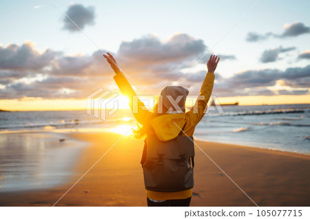 Tourist in yellow jacket enjoying sea landscape at sunset. Lifestyle, travel, nature, active life. 105077715