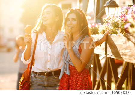 Two young female friends having fun and eating ice cream. Young women enjoy summer and vacation. 105078372