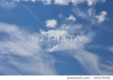 Cloudy blue sky background with white swirling clouds. 105078438