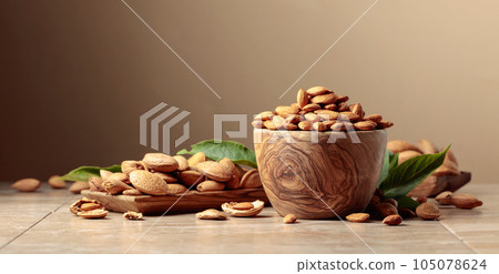 Almond nuts in wooden dishes on a ceramic table. Almond nuts in wooden dishes on a ceramic table. 105078624
