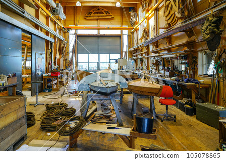 Interior view of a carpentry workshop with many tools an old wooden boat and its unfinished replica Interior view of a carpentry workshop with many tools an old wooden boat and its unfinished replica 105078865