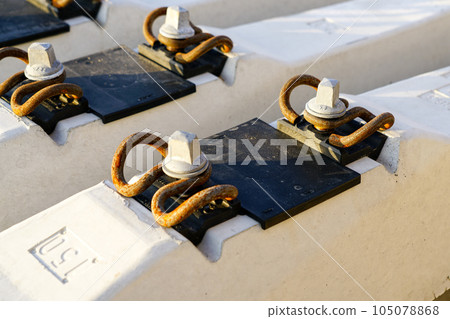 Before track repair stacked new white reinforced concrete railroad track sleepers with rail mounts 105078868