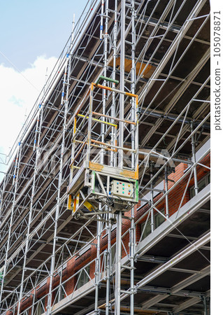 Restoration of the facade of a historic house using scaffolding with temporary elevator platform 105078871