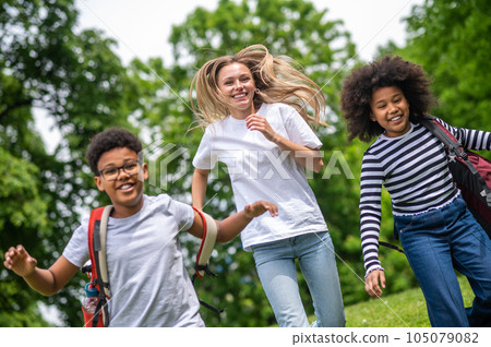 Blonde girl and two african american teens playing in the park 105079082