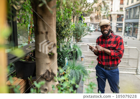 Man in a cap in the street looking at the plants 105079228