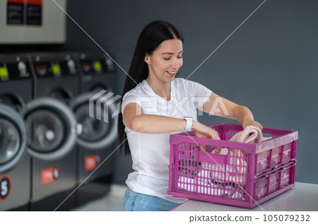 Woman in the public room to wash her cloths, self service commercial laundry and drying machine in a public room. Woman in the public room to wash her cloths, self service commercial laundry and drying machine in a public room. 105079232