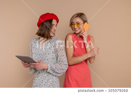 Two women friends wearing elegantdresses using digital tablet and mobile phone. Two women friends wearing elegantdresses using digital tablet and mobile phone. 105079268