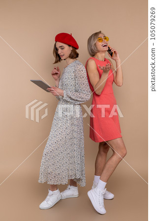 Two women friends wearing elegantdresses using digital tablet and mobile phone. 105079269