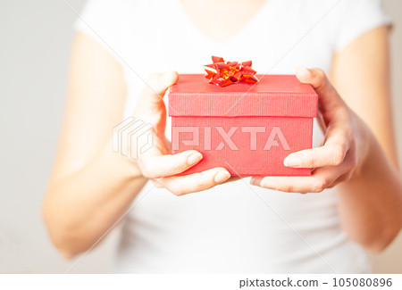 Female hands opening small gift in a red box. Female hands opening small gift in a red box. 105080896