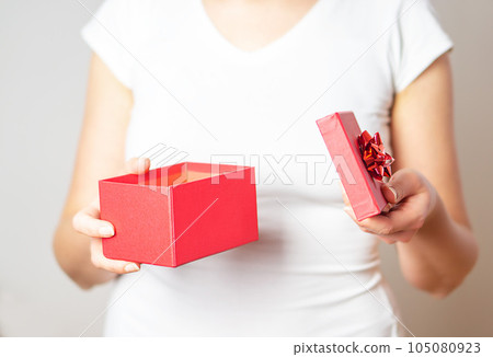 Close up shot of the female hands opening small gift in red box.  105080923