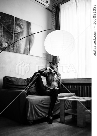 Playful attractive sexy woman in leather cat suit on the couch. black and white Playful attractive sexy woman in leather cat suit on the couch. black and white 105081055