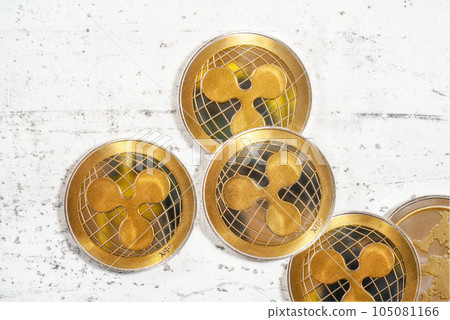 Tabletop photo - detail of golden ripple cryptocurrency coins scattered on white board 105081166
