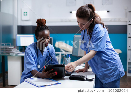 Diverse medical healthcare staff team looking at digital tablet screen in modern professional clinic office. African american nurse comparing data with coworker in hospital workplace Diverse medical healthcare staff team looking at digital tablet screen in modern professional clinic office. African american nurse comparing data with coworker in hospital workplace 105082024