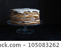 a whole round honey cake on a stand against a dark background 105083262