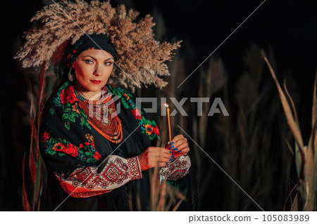 Mysterious ukrainian woman with candle, she in traditional costume outdoors Mysterious ukrainian woman with candle, she in traditional costume outdoors 105083989