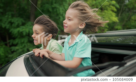 Adorable happy little boys children in open car sunroof during road trip, summer Adorable happy little boys children in open car sunroof during road trip, summer 105084009