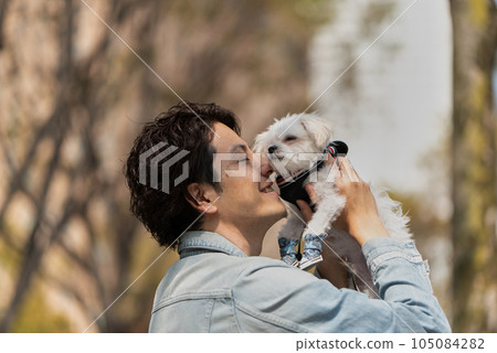 男人在公園裡親吻他的寵物狗 男人在公園裡親吻他的寵物狗 105084282