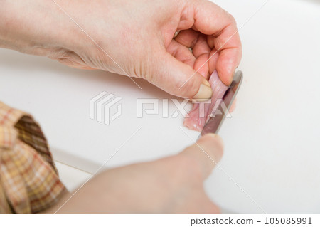 [Housewife preparing yakitori gizzards with a knife] 105085991