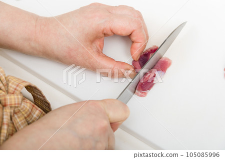 [Housewife preparing yakitori gizzards with a knife] 105085996
