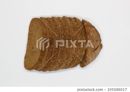 Sliced black bread. Dark rye bread with cumin cut into even pieces on a white background. Wheat black bread on the table. Isolated. Bran from grain. Healthy food. Vegetarian food. Ecological friendly 105086017