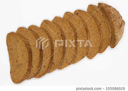 Sliced black bread. Dark rye bread with cumin cut into even pieces on a white background. Wheat black bread on the table. Isolated. Bran from grain. Healthy food. Vegetarian food. Ecological friendly Sliced black bread. Dark rye bread with cumin cut into even pieces on a white background. Wheat black bread on the table. Isolated. Bran from grain. Healthy food. Vegetarian food. Ecological friendly 105086020