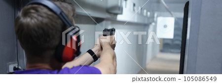 Man shoots at target with pistol in shooting range. Man shoots at target with pistol in shooting range. 105086549