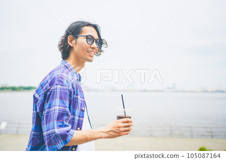 一個男人拿著外賣咖啡沿著海灘散步 105087164