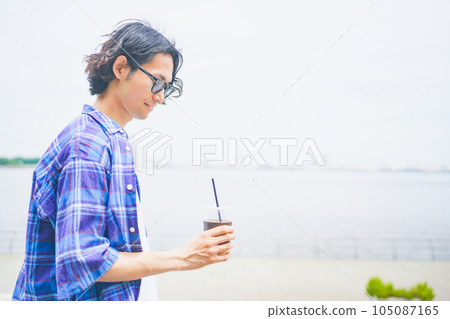 一個男人拿著外賣咖啡沿著海灘散步 105087165