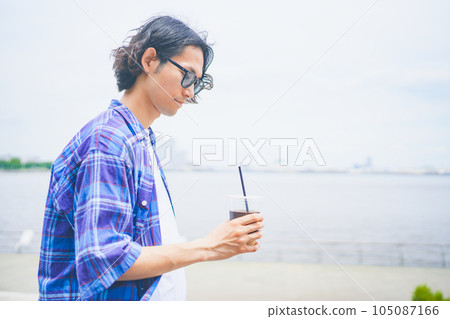 A man walking along the beach with take-out coffee A man walking along the beach with take-out coffee 105087166