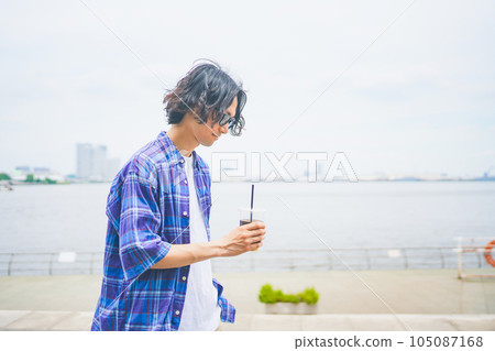 一個男人拿著外賣咖啡沿著海灘散步 105087168