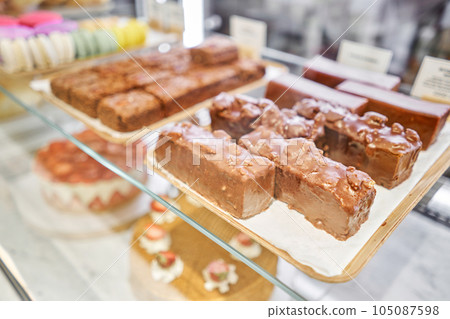 A variety of cakes covered with chocolate and decorated with pistachio mousse. A showcase in a pastry shop with delicious desserts with fresh berries and cream. Delicious pastries in the coffee shop. A variety of cakes covered with chocolate and decorated with pistachio mousse. A showcase in a pastry shop with delicious desserts with fresh berries and cream. Delicious pastries in the coffee shop. 105087598