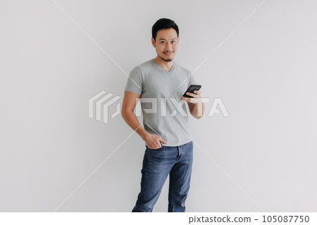 Happy handsome man in jeans using smartphone isolated on white background. 105087750