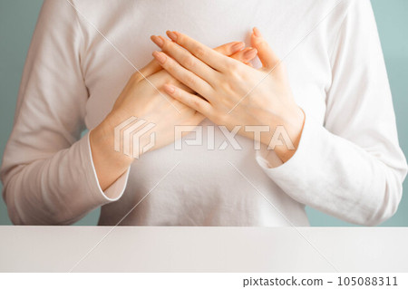 A woman putting her hand on her chest 105088311