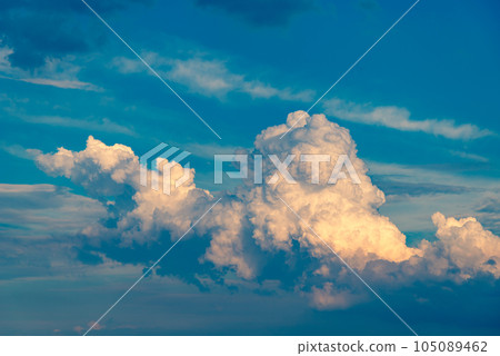A cumulonimbus cloud with shadows rising in the evening summer sky a-3 warm colors 105089462