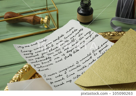 Letter with text on golden tray, ink bottle and stamp on green wooden background, close up Letter with text on golden tray, ink bottle and stamp on green wooden background, close up 105090263