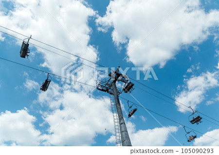 Mountain four-seater chairlift on the background of a blue cloud sky. 105090293