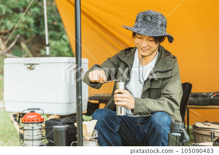 Young male camper camping solo at campsite (coffee mill) 105090483