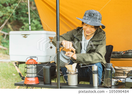 Young male camper (coffee dripper) camping solo at campsite 105090484