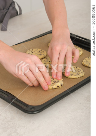 teenager boy's hands making american chocolate chip cookies at home. vertical shot of young chef hands with baking sheet. 105090562